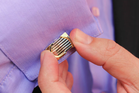 Male hand buttons cufflinks in purple shirt