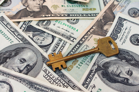 The keys on a background of money. The concept of buying or renting a home.の写真素材