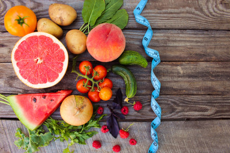 Fruits, vegetables and in measure tape in diet on wooden backgroundの写真素材