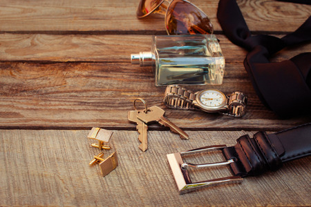 Men accessories: sunglasses, bag, wrist watch, cufflinks, comb, strap, keys, tie, perfume on the old wood background. Toned image.の写真素材