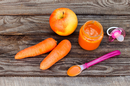 Fruit puree, carrot, apple and pacifier on wooden backgroundの写真素材