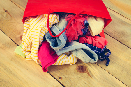 Women's clothing falls out of paper shopping bags on wooden background. Toned image.の写真素材