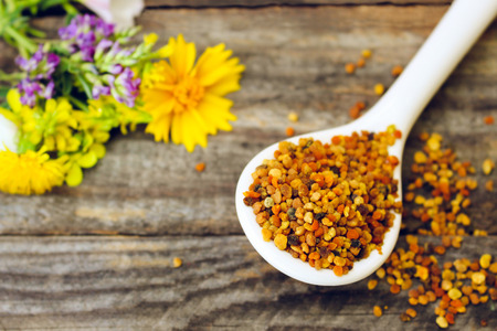 Bee pollen and field flowers on old wooden background. Toned image.の写真素材