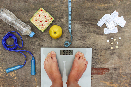 Concept of different ways to lose weight. Scales, tape measure, apple, oatmeal, jump rope, water, medicine.の写真素材