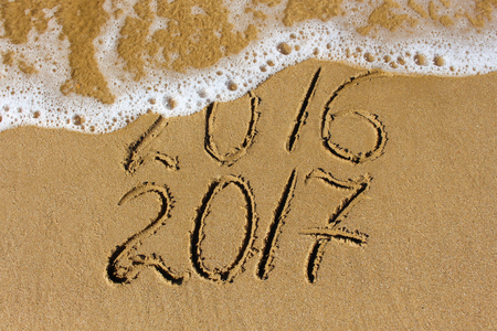2016 and 2017 year written on sandy beach sea.の写真素材