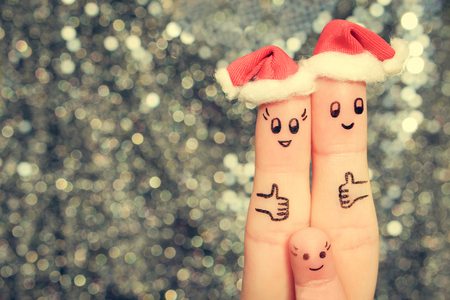 Finger art of family celebrates Christmas. Concept of group of people laughing in new year hats. Happy couple showing thumbs up. Toned image.の写真素材