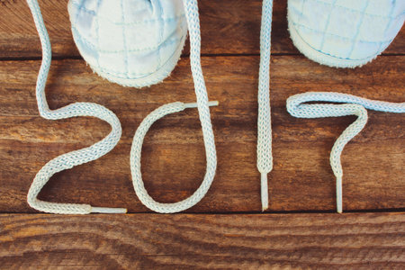 2017 new year written laces of children's shoes on old wooden background. Toned image