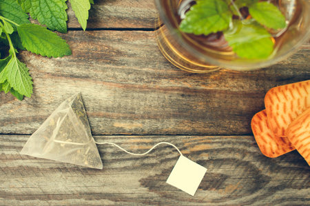 Tea bag, mint, cookie and cup of tea. Toned image. Top view.