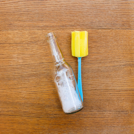 Brush for washing dishes and bottle on table.の写真素材