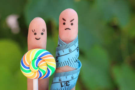 Finger art of couple with meter and candy. Concept of man angry for woman wants to lose weight.の写真素材