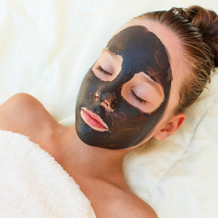 Beautiful girl with facial black clay mask.の写真素材