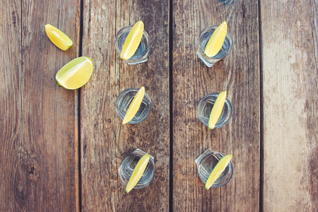 Vodka and lime slices on a wooden background. Toned image. Top view.の写真素材