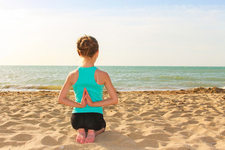 Girl practicing yoga on the beach.の写真素材