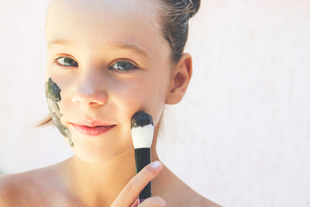 Beautiful girl with facial black clay mask. Toned image.の写真素材
