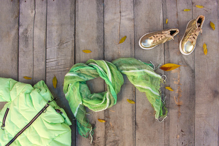 Children's autumn clothes and yellow leaves on old wooden background. Top view. Flat lay.の写真素材