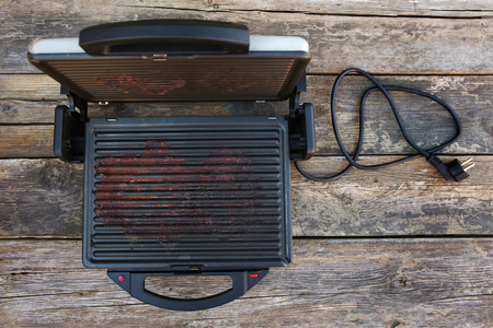 Dirty electric grill on old wooden background. Top view. Flat lay.の写真素材