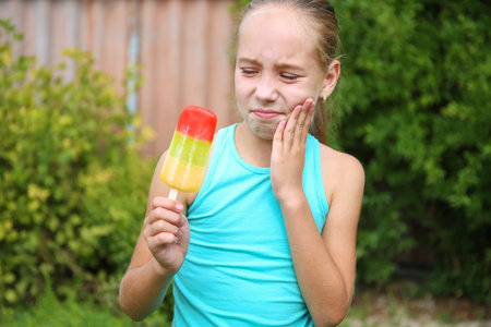 Girl has toothache from cold ice cream.