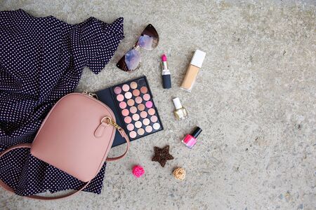 Summer women's clothing: dress, cosmetics, sunglasses, handbag on stone background. Top view. Flat lay.の写真素材