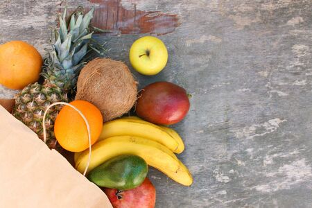 Paper bag with fruits and vegetables on old wooden background. Top view.の写真素材