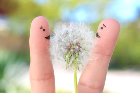 Fingers art of happy couple. Man is giving flowers to woman.