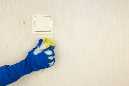 Woman's hand washes dirty wall.
