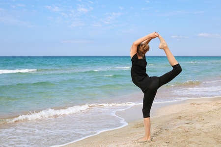 Girl practicing yoga on beach.の写真素材