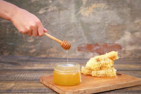 Honey in a jar and honeycomb on an old wooden background.