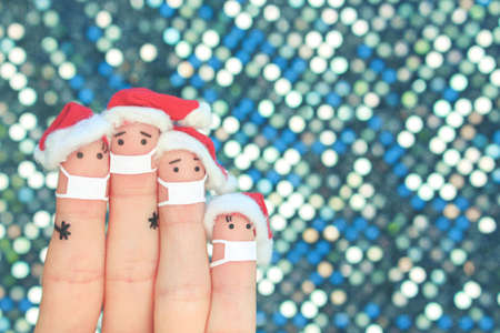 Fingers art of family in medical mask from COVID-2019 celebrates Christmas. Concept of people in New Year hats.の写真素材