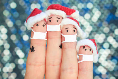 Fingers art of family in medical mask from COVID-2019 celebrates Christmas. Concept of people in New Year hats.の写真素材