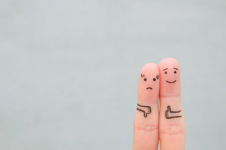 Fingers art of couple. Woman showing thumb down and man showing thumb up. Concept of disagreement in family.の写真素材