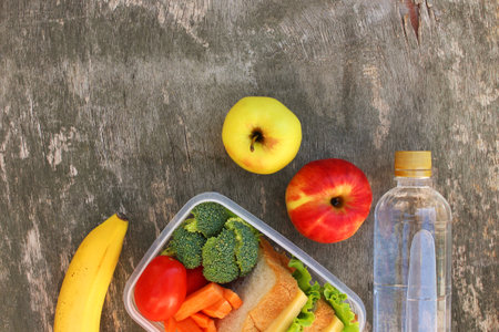 Sandwiches, fruits and vegetables in food box, water on old wooden background. Top view. Flat lay.の写真素材