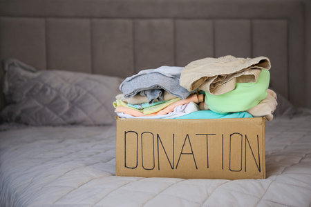 Donation box with clothes on the bed.
