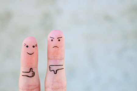 Finger art of couple. Woman showing thumbs up and man showing thumbs down. Concept of disagreement in family.の素材 [FY310202516257]