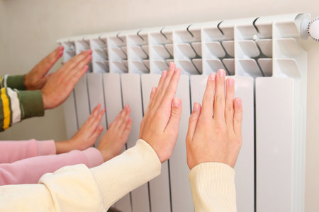 The family warms their hands near the radiator.の写真素材