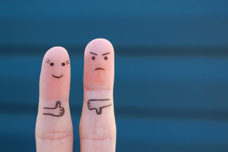 Finger art of couple. Woman showing thumbs up and man showing thumbs down. Concept of disagreement...