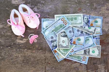 Pink pacifiers and children's shoes on the background of money.の写真素材