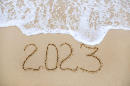 2023 year written on sandy beach sea. top view. flat lay.