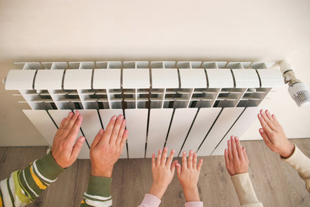The family warms their hands near the radiator.の写真素材