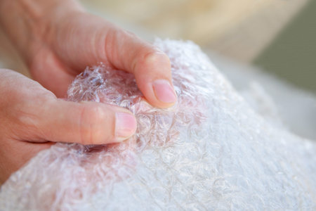 Women's hands pop bubbles on bubble wrap, packaging material, antistress.
