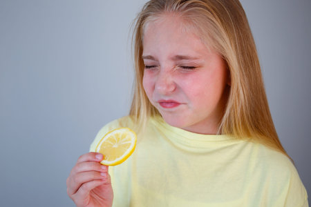 The child eats a sour lemon. The girl wrinkled her face.の写真素材