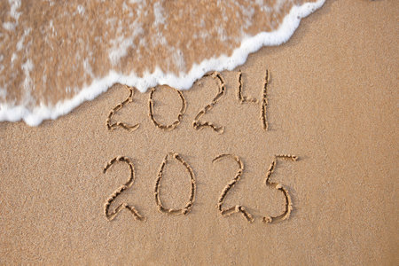 2024, 2025 years written on sandy beach sea. Wave washes away 2024. Happy New Year!の写真素材