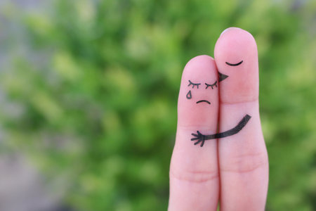 Fingers art of displeased couple. Woman cries, man reassures her. He kisses and hugs her.の写真素材
