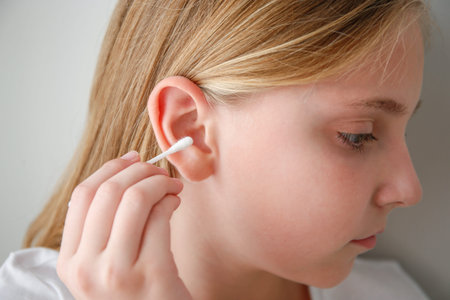 The child cleans the auricle with a cotton swab