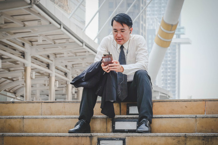 Handsome businessman sitting and using smart phoneの写真素材