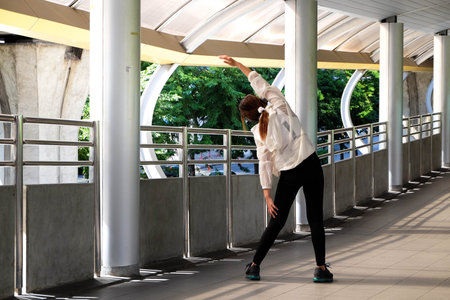 Woman in fashion sportswear doing warm up, preparing for workout in the city