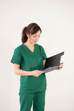 Portrait of female doctor in medical uniform reading reportの写真素材