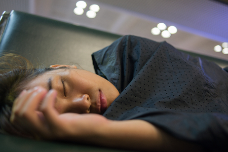 Tired girl sleeping in the airport because flight delayの写真素材