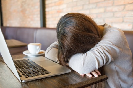 Tired girl sleeping beside a cup of coffeeの写真素材