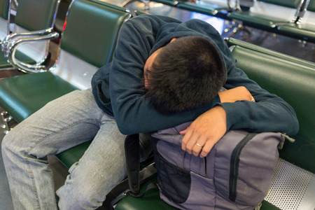 Drowsy man drooping head on backpack to sleepの写真素材