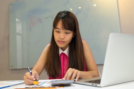 Young employee working on sales report and calculatorの写真素材